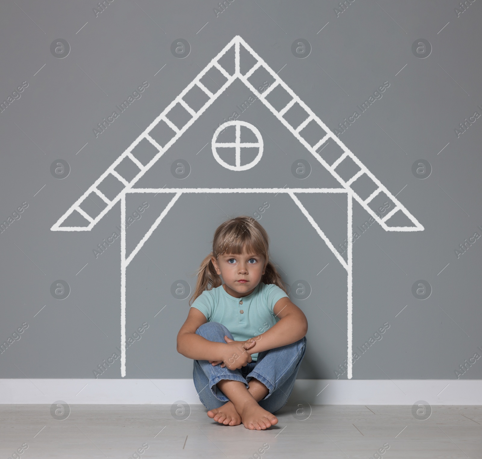 Orphanage. Sad little girl on floor near grey wall with drawing of house Image of Orphanage. Sad little girl on floor near grey wall with drawing of house