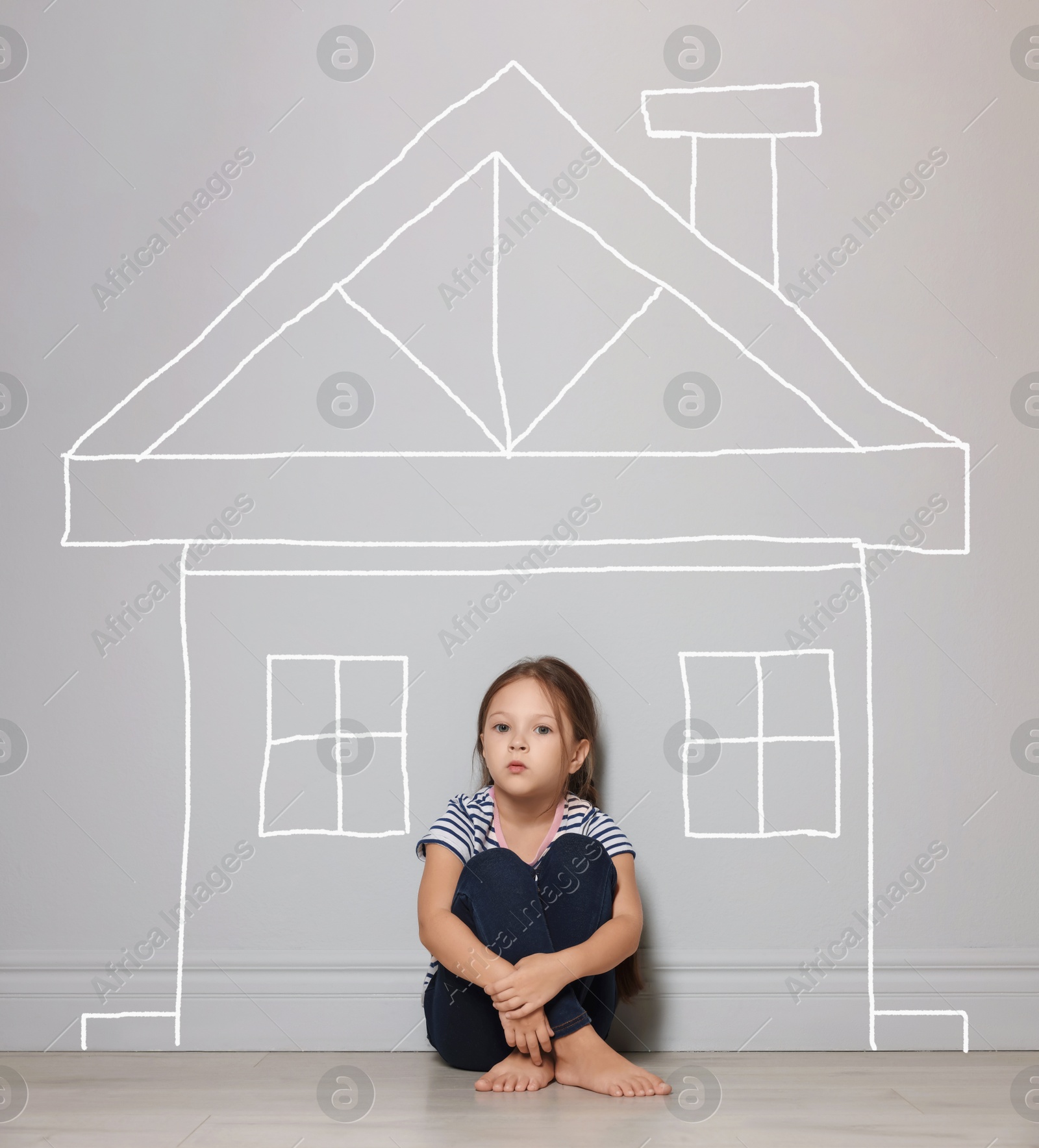 Image of Orphanage. Sad little girl on floor near grey wall with drawing of house