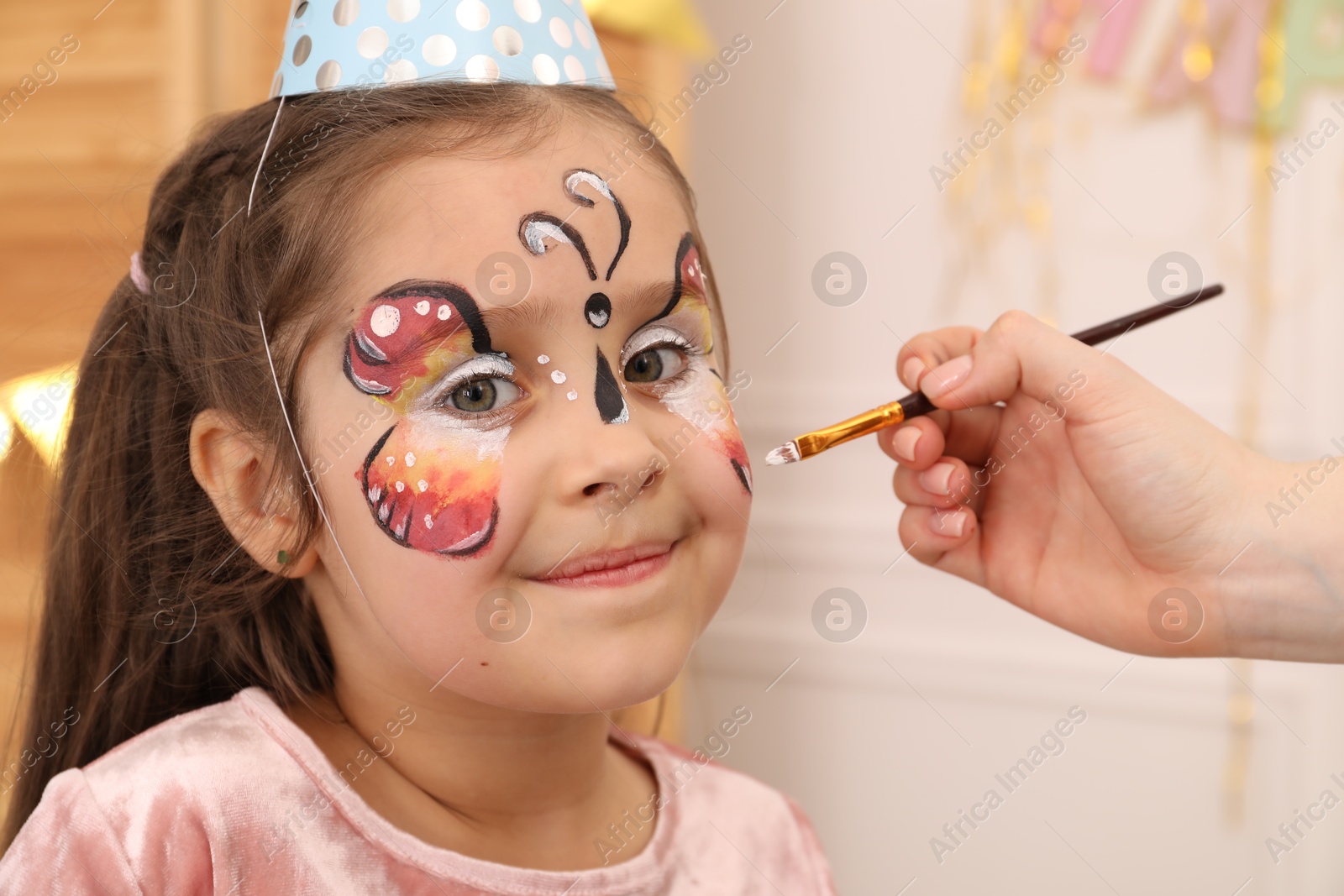 Animator drawing butterfly on girl's face indoors, closeup Photo of Animator drawing butterfly on girl's face indoors, closeup