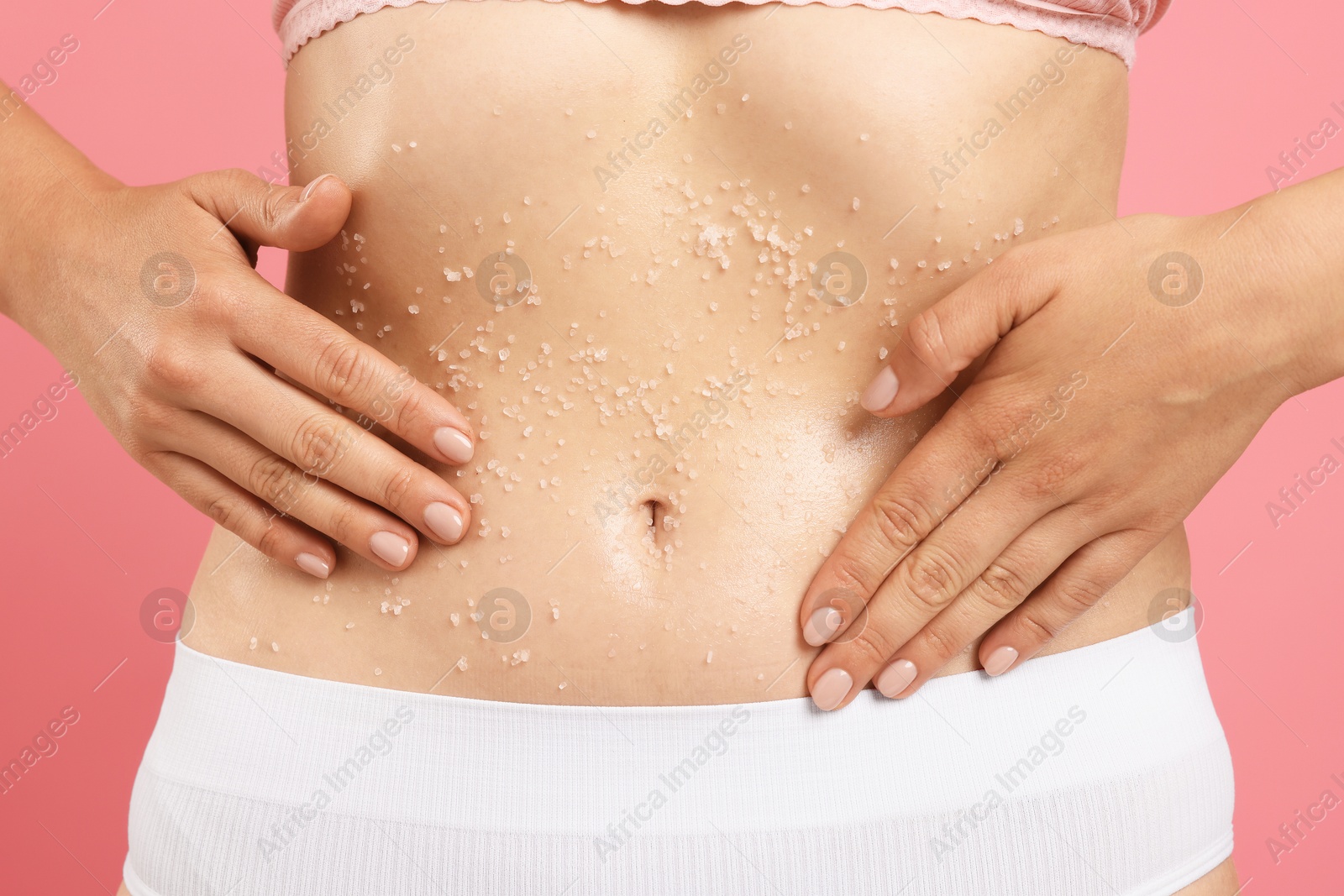 Woman applying body scrub onto her belly against pink background, closeup Photo of Woman applying body scrub onto her belly against pink background, closeup