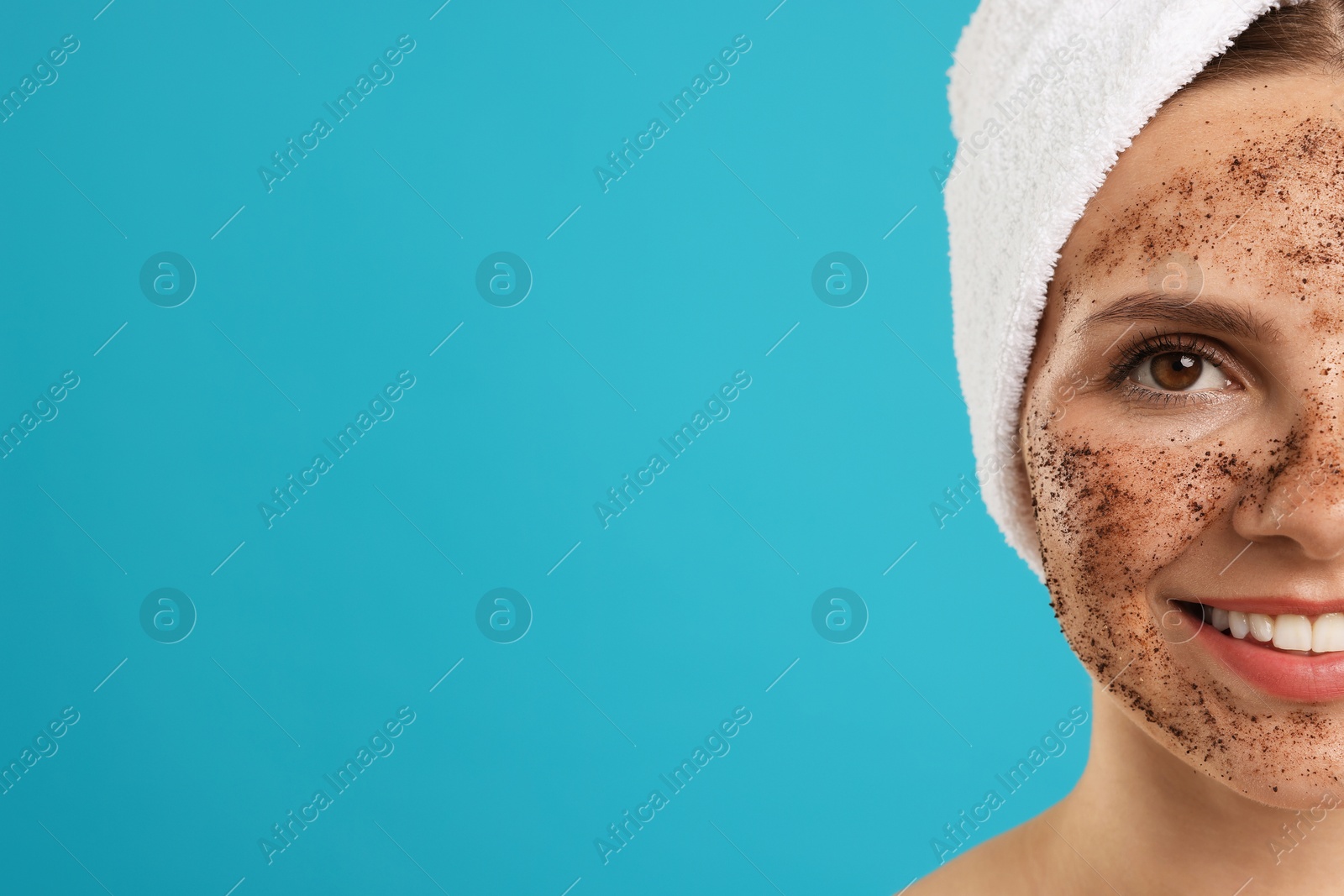 Smiling woman with body scrub on her face against light blue background, closeup. Space for text Photo of Smiling woman with body scrub on her face against light blue background, closeup. Space for text