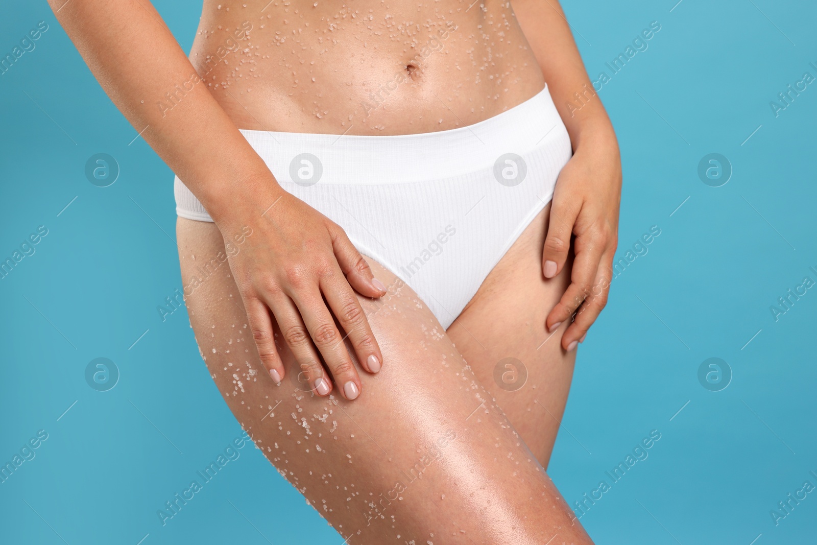 Woman with body scrub on her skin against light blue background, closeup Photo of Woman with body scrub on her skin against light blue background, closeup