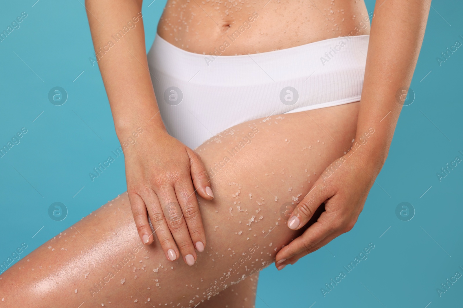 Woman with body scrub on her skin against light blue background, closeup Photo of Woman with body scrub on her skin against light blue background, closeup