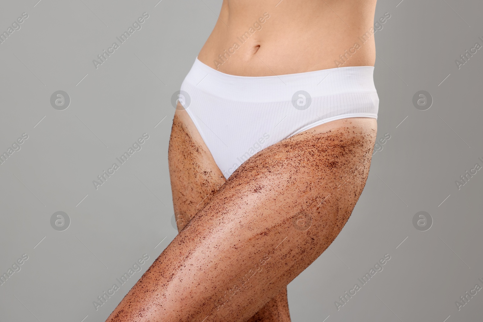 Woman with body scrub on her legs against grey background, closeup Photo of Woman with body scrub on her legs against grey background, closeup