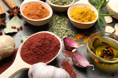 Photo of Different spices and oil on grey table, closeup