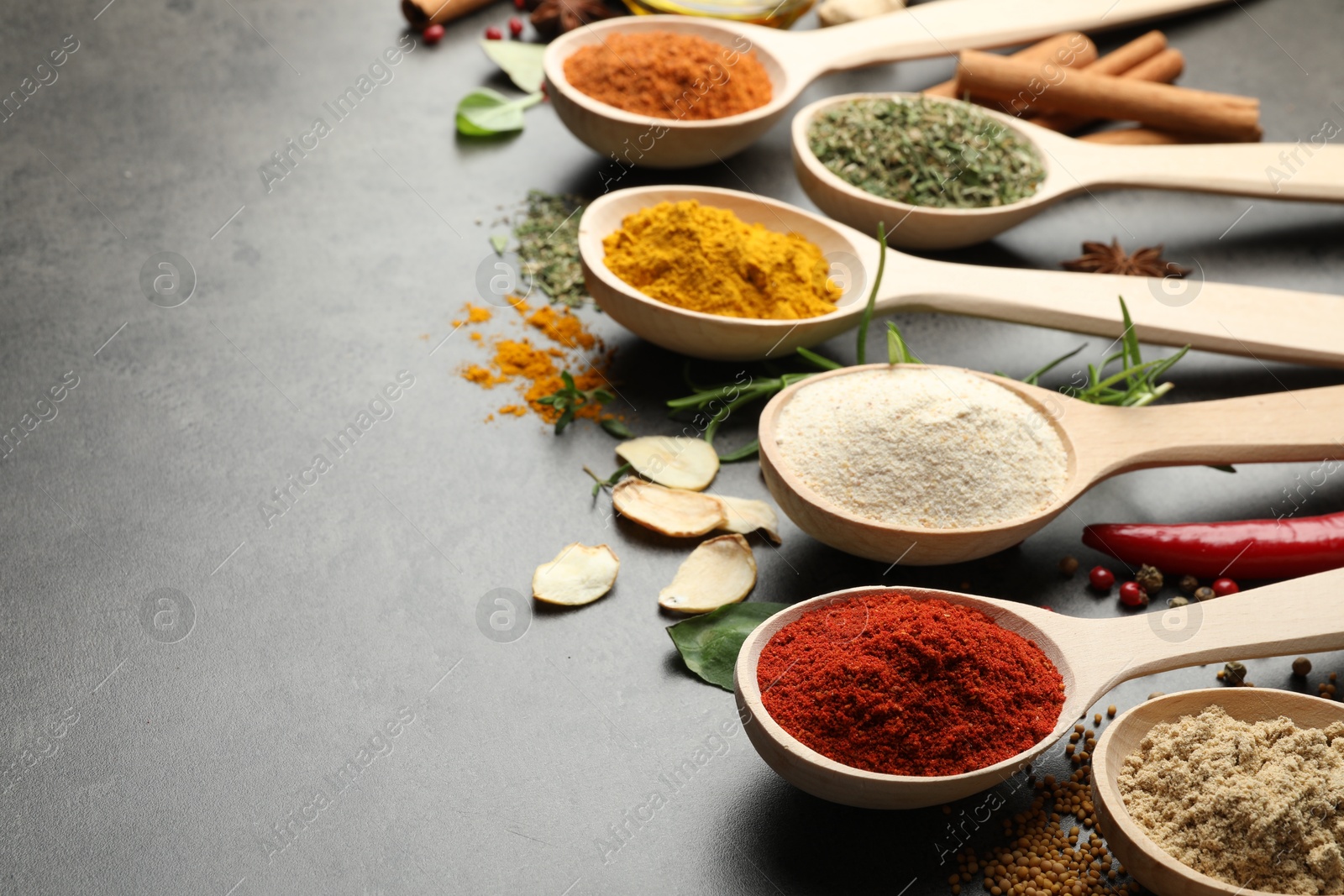 Many different spices in spoons on grey table, closeup. Space for text Photo of Many different spices in spoons on grey table, closeup. Space for text