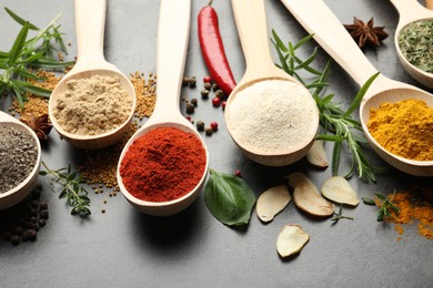 Photo of Many different spices in spoons on grey table, closeup
