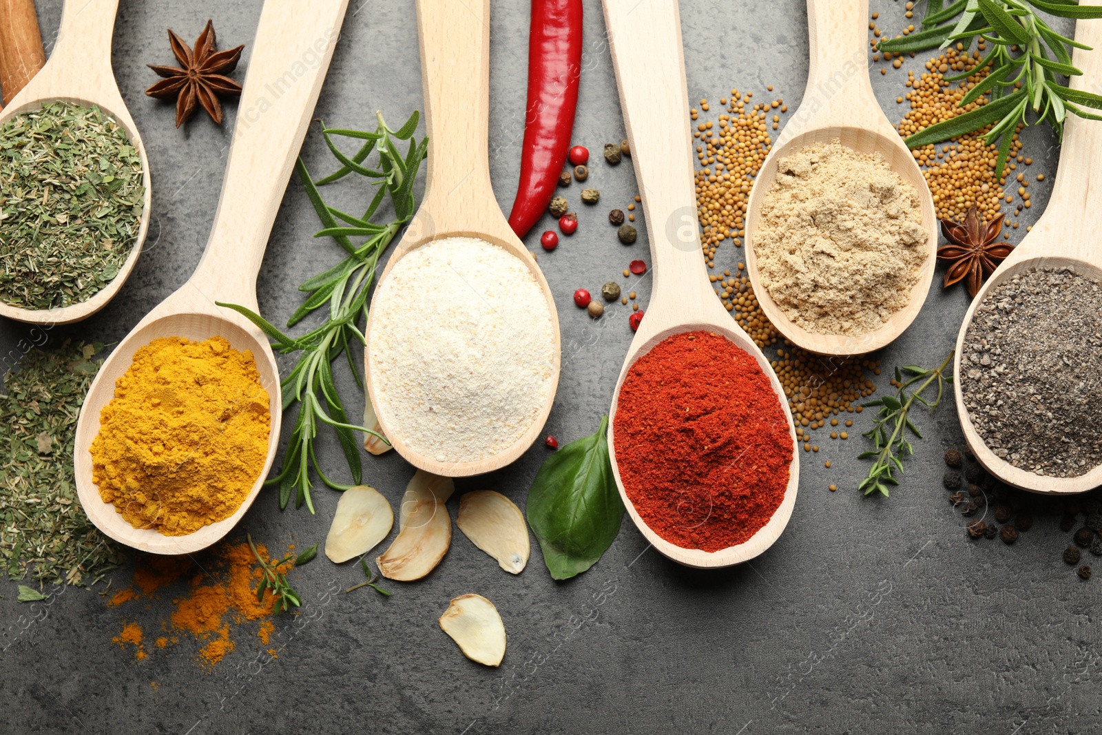 Many different spices in spoons on grey table, flat lay Photo of Many different spices in spoons on grey table, flat lay