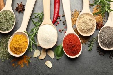 Photo of Many different spices in spoons on grey table, flat lay