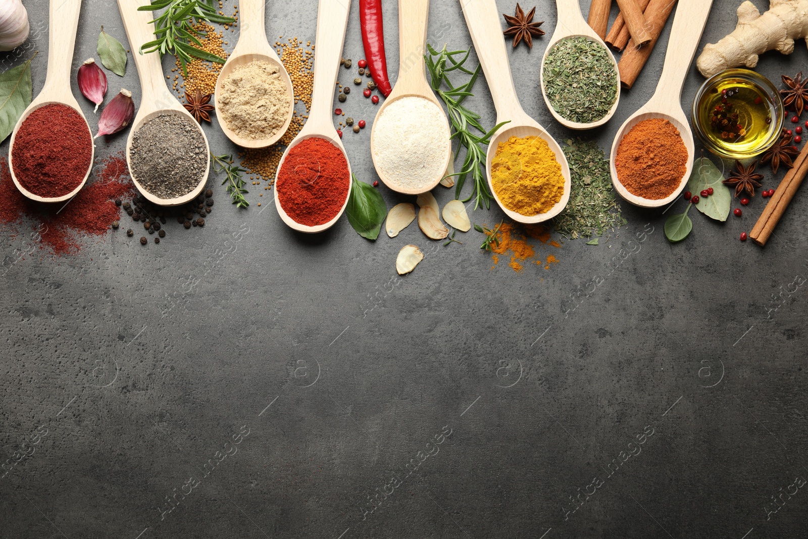 Photo of Many different spices in spoons on grey table, flat lay. Space for text