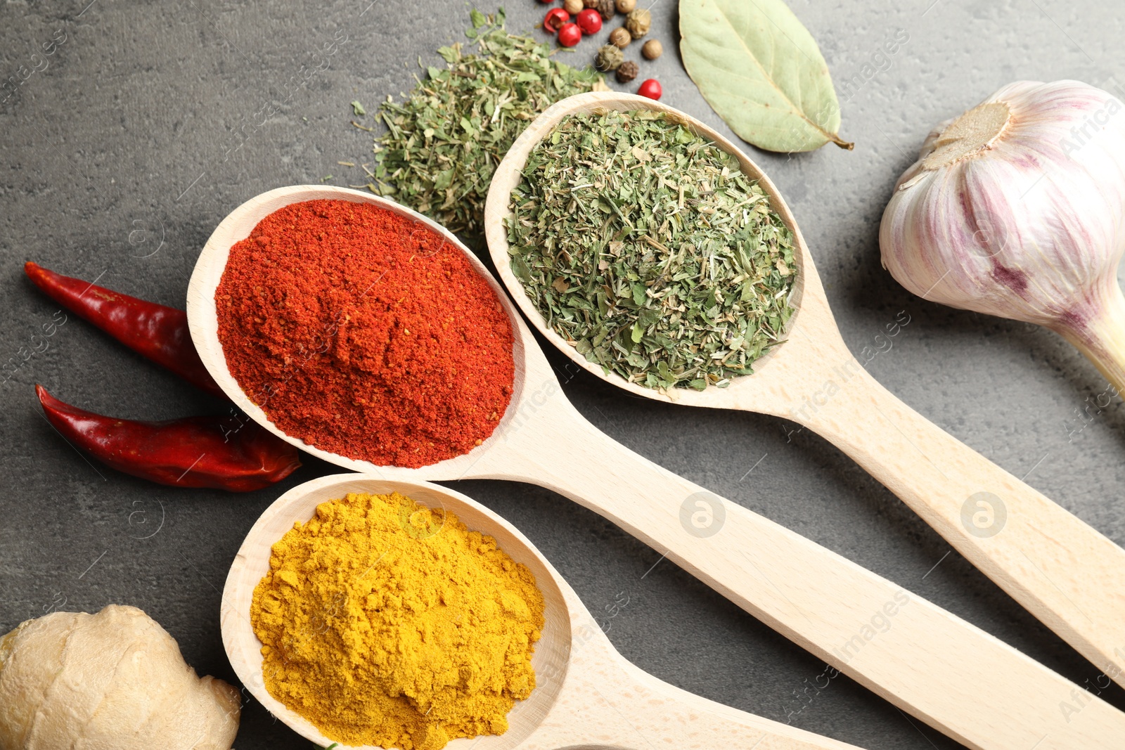 Many different spices in spoons on grey table, flat lay Photo of Many different spices in spoons on grey table, flat lay