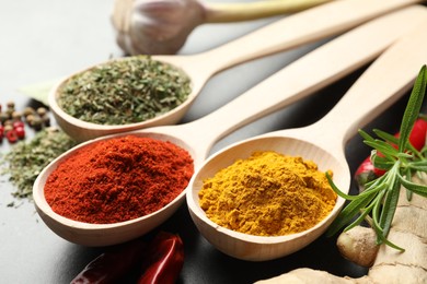 Photo of Many different spices in spoons on grey table, closeup