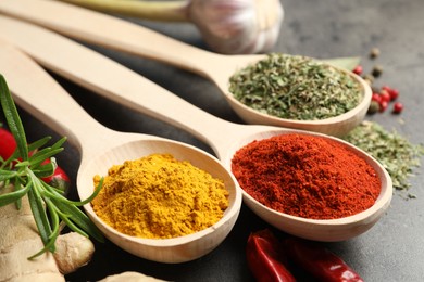 Photo of Many different spices in spoons on grey table, closeup