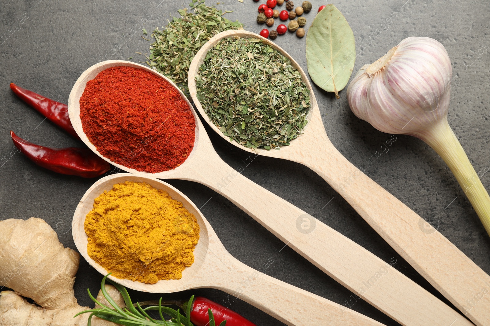 Many different spices in spoons on grey table, flat lay Photo of Many different spices in spoons on grey table, flat lay