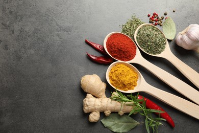 Photo of Many different spices in spoons on grey table, flat lay. Space for text