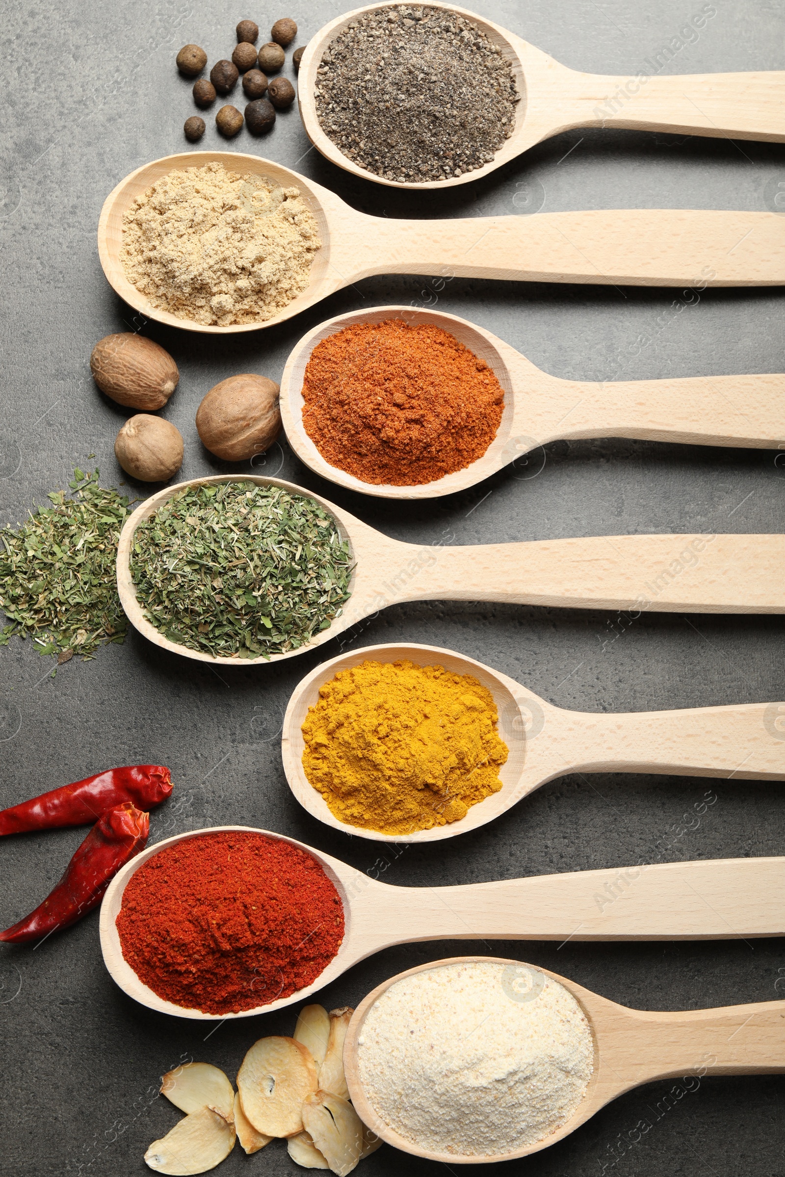 Many different spices in spoons on grey table, flat lay Photo of Many different spices in spoons on grey table, flat lay
