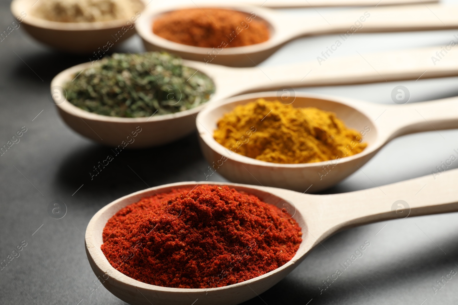 Many different spices in spoons on grey table, closeup Photo of Many different spices in spoons on grey table, closeup