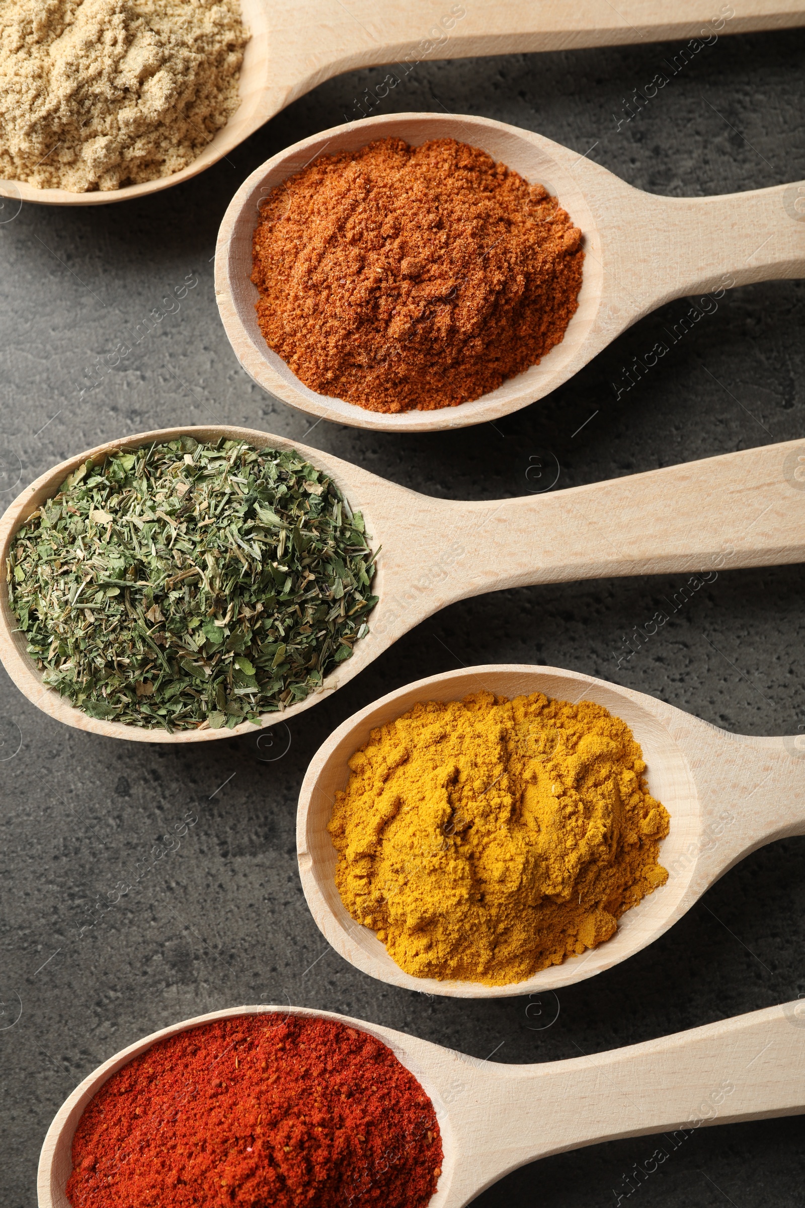 Many different spices in spoons on grey table, flat lay Photo of Many different spices in spoons on grey table, flat lay