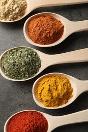 Photo of Many different spices in spoons on grey table, flat lay