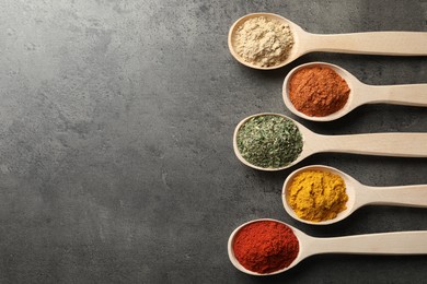 Photo of Many different spices in spoons on grey table, flat lay. Space for text
