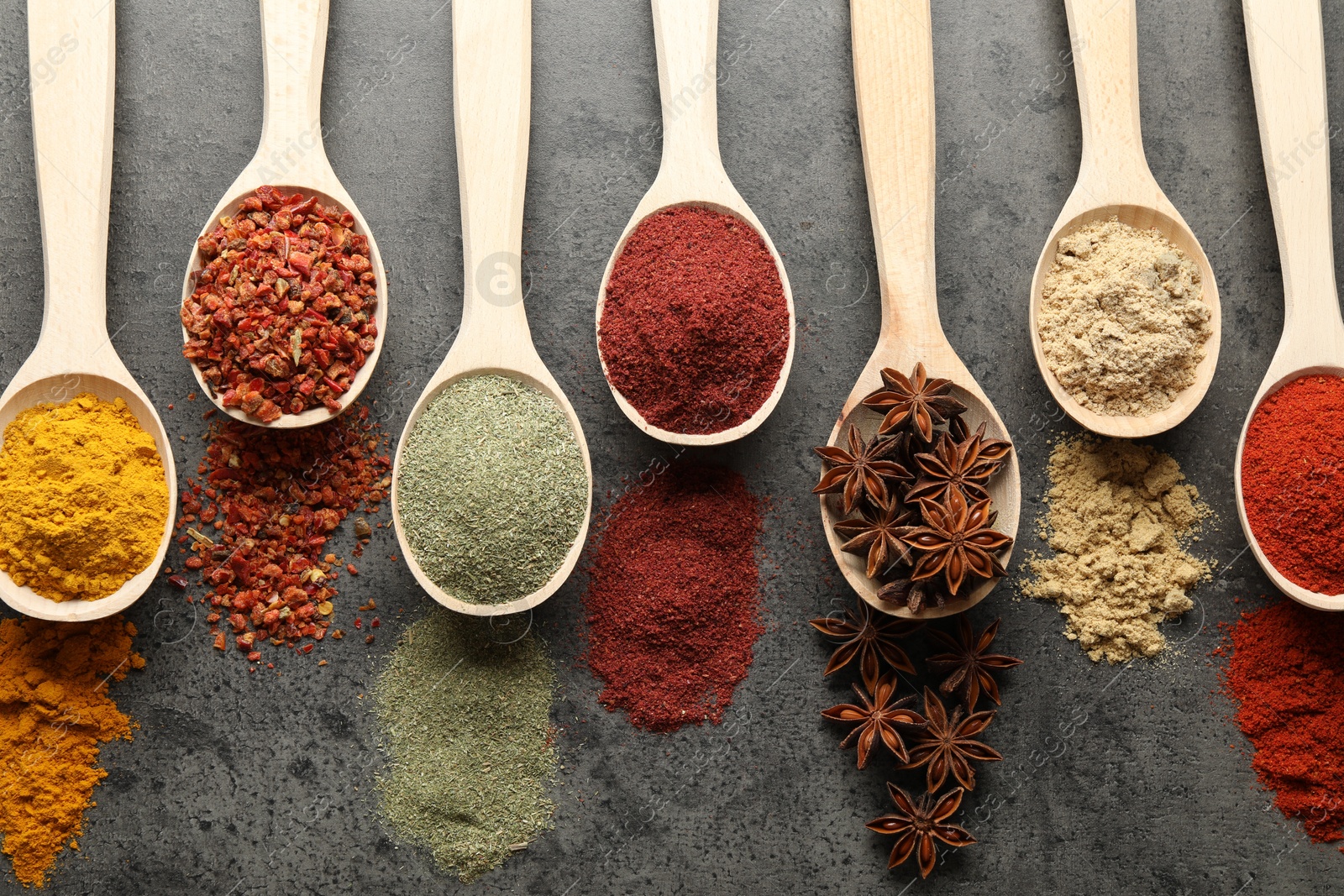 Many different spices in spoons on grey table, flat lay Photo of Many different spices in spoons on grey table, flat lay