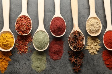 Photo of Many different spices in spoons on grey table, flat lay