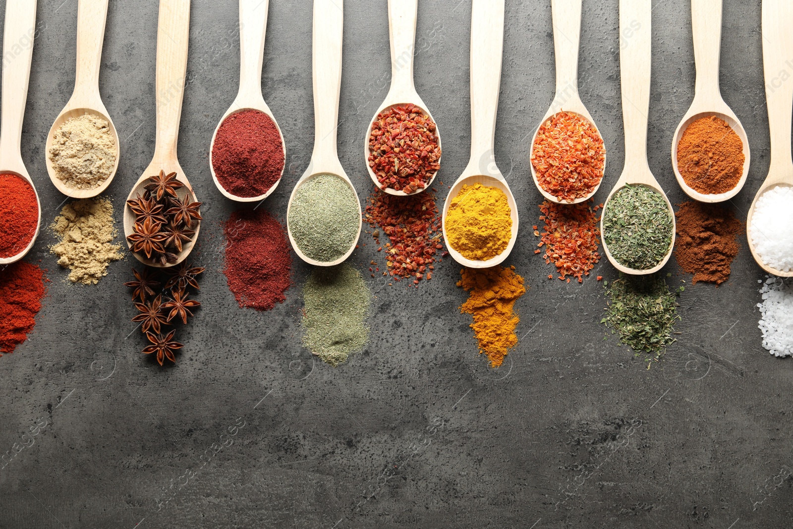 Many different spices in spoons on grey table, flat lay. Space for text Photo of Many different spices in spoons on grey table, flat lay. Space for text