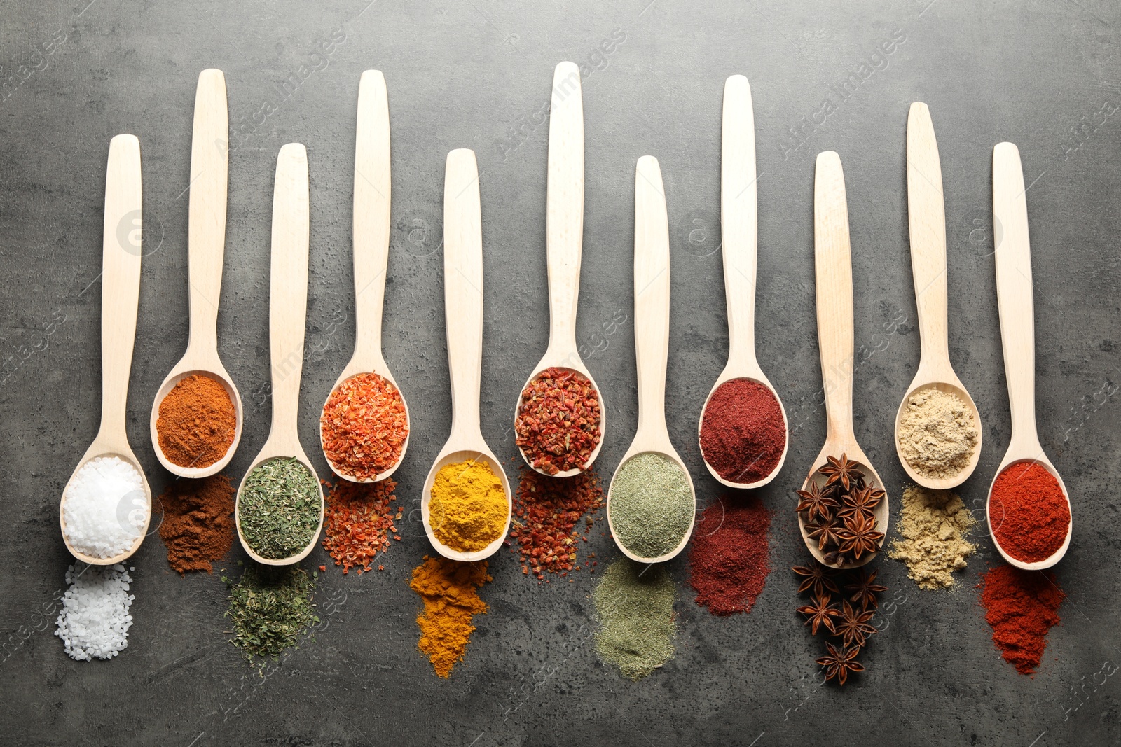 Many different spices in spoons on grey table, flat lay Photo of Many different spices in spoons on grey table, flat lay