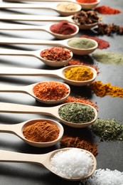 Photo of Many different spices in spoons on grey table, closeup