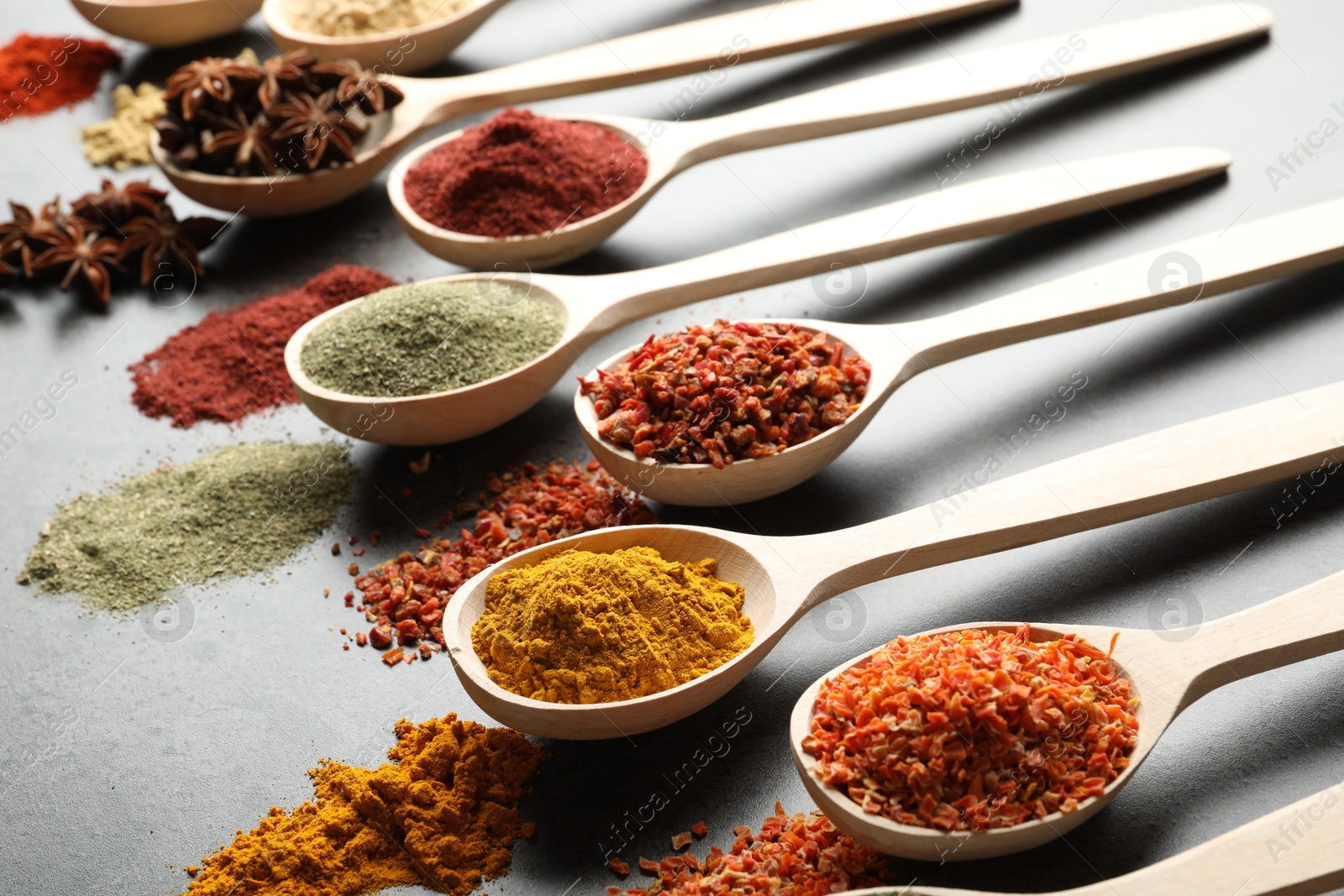 Many different spices in spoons on grey table, closeup Photo of Many different spices in spoons on grey table, closeup