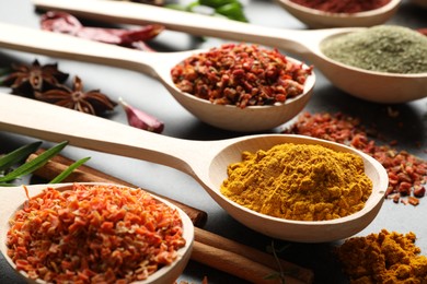 Photo of Many different spices in spoons on grey table, closeup