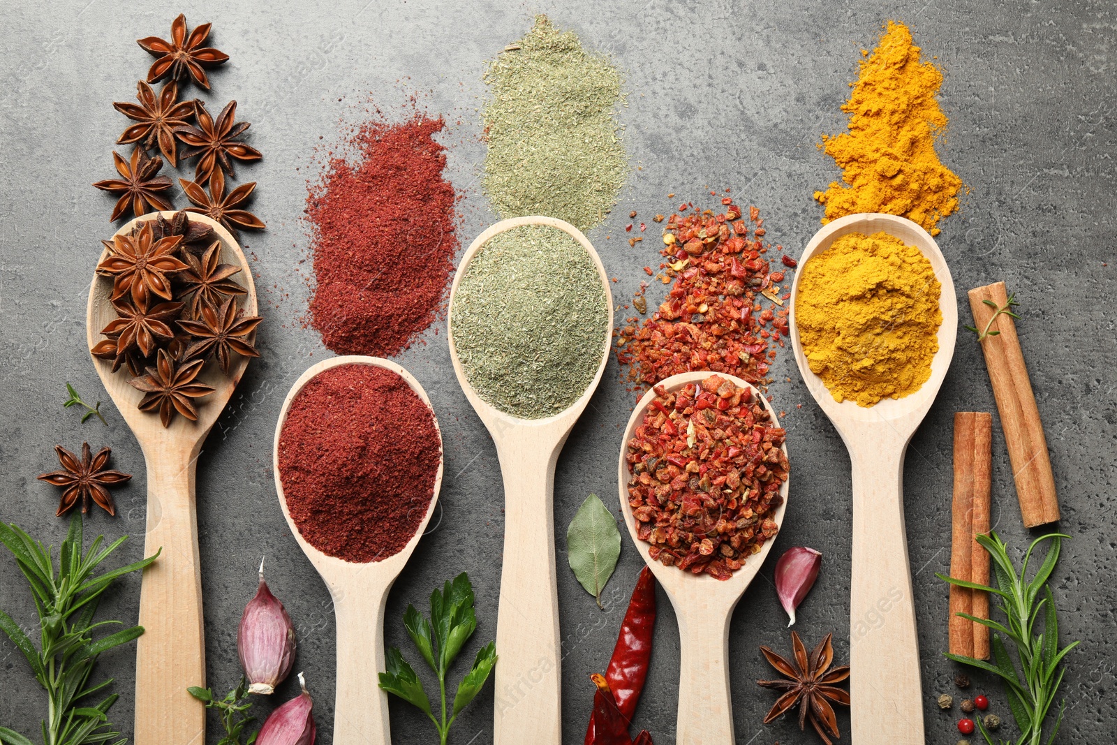 Many different spices in spoons on grey table, flat lay Photo of Many different spices in spoons on grey table, flat lay