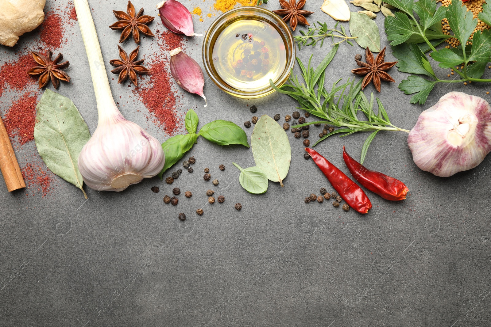 Different spices and oil on grey table, flat lay. Space for text Photo of Different spices and oil on grey table, flat lay. Space for text