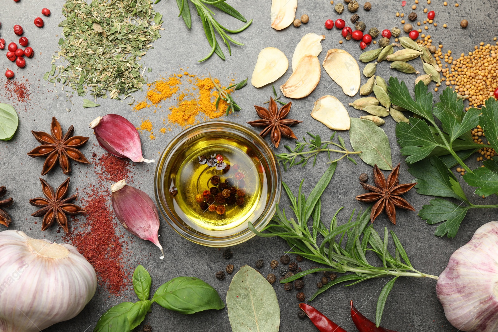 Different spices and oil on grey table, flat lay Photo of Different spices and oil on grey table, flat lay