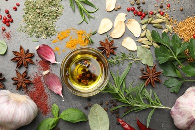 Photo of Different spices and oil on grey table, flat lay