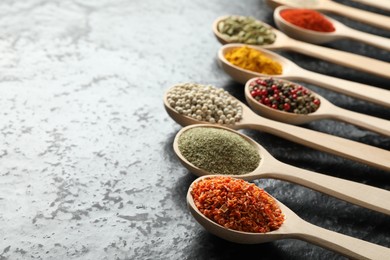 Photo of Many different spices in spoons on black table, closeup. Space for text