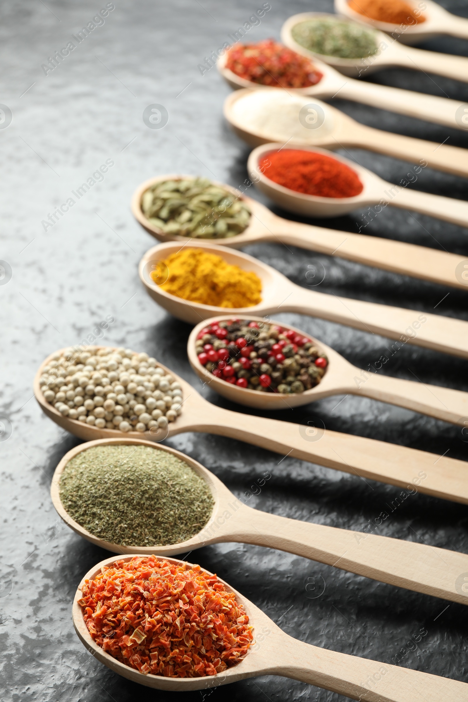 Many different spices in spoons on black table, closeup Photo of Many different spices in spoons on black table, closeup