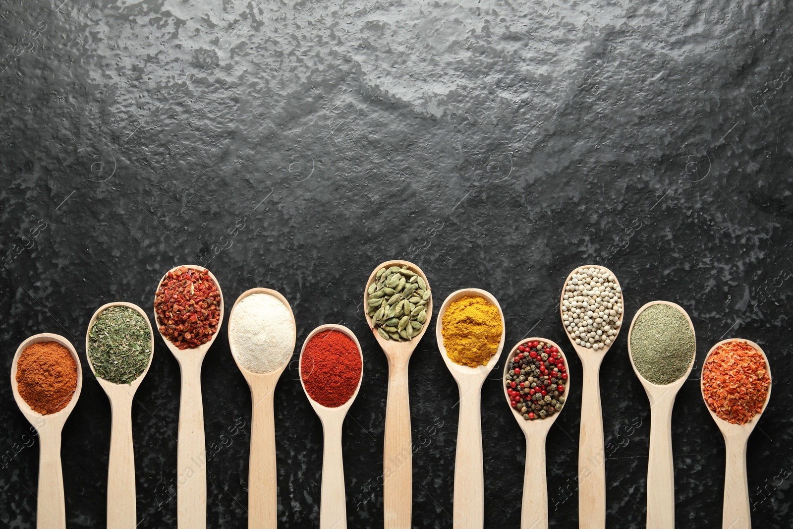 Many different spices in spoons on black table, flat lay. Space for text Photo of Many different spices in spoons on black table, flat lay. Space for text