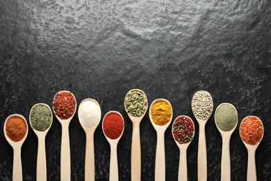 Photo of Many different spices in spoons on black table, flat lay. Space for text