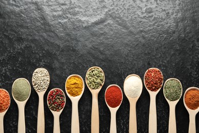 Photo of Many different spices in spoons on black table, flat lay. Space for text