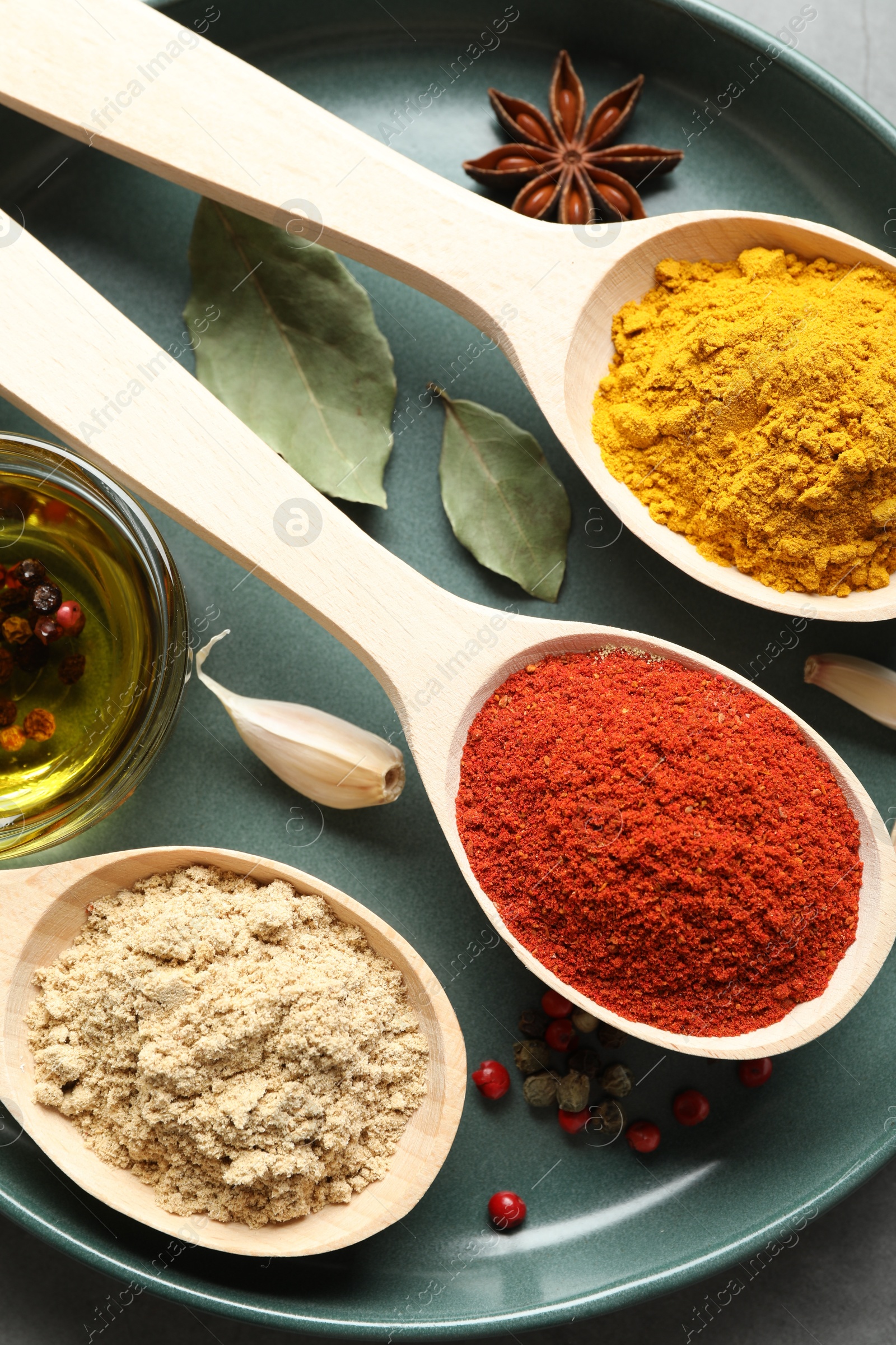 Many different spices in spoons on grey table, closeup Photo of Many different spices in spoons on grey table, closeup