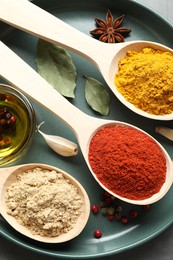 Photo of Many different spices in spoons on grey table, closeup