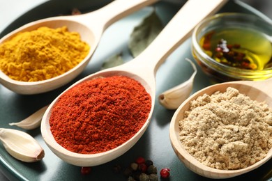 Photo of Many different spices in spoons on grey table, closeup