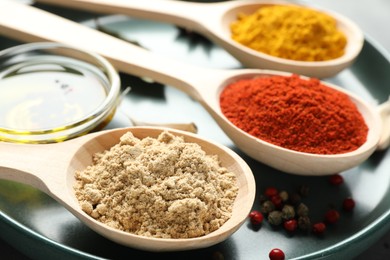 Photo of Many different spices in spoons on grey table, closeup