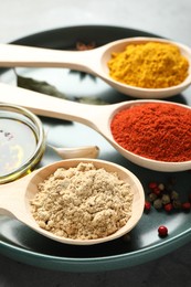 Photo of Many different spices in spoons on grey table, closeup