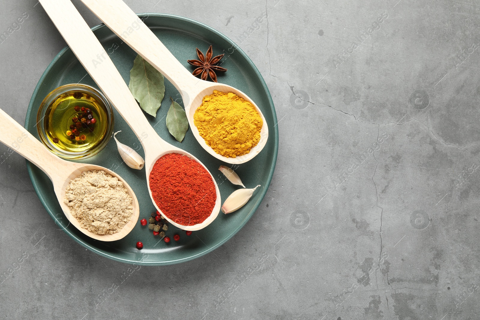 Many different spices in spoons on grey table, top view. Space for text Photo of Many different spices in spoons on grey table, top view. Space for text