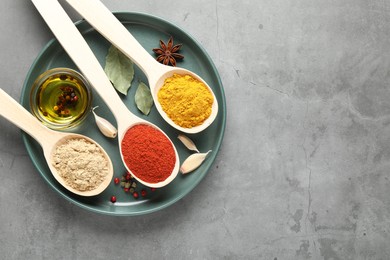 Photo of Many different spices in spoons on grey table, top view. Space for text