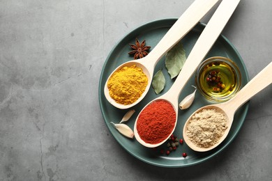 Photo of Many different spices in spoons on grey table, top view. Space for text