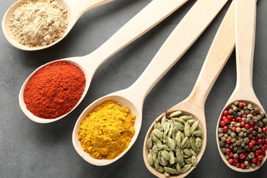 Photo of Many different spices in spoons on grey table, flat lay