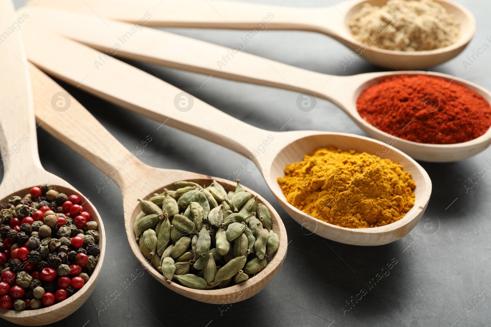 Many different spices in spoons on grey table, closeup Photo of Many different spices in spoons on grey table, closeup